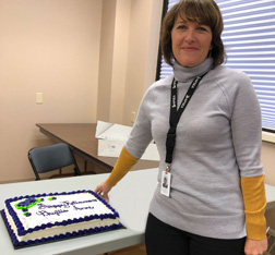 Phyllis standing next to a table with her retirement cake